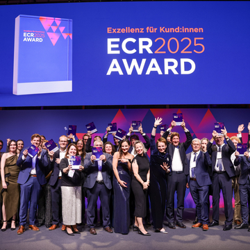 Gruppenbild der jubelnden Gewinnerteams in eleganter Abendgarderobe vom ECR Award 2025 auf großer Bühne mit Trophäen